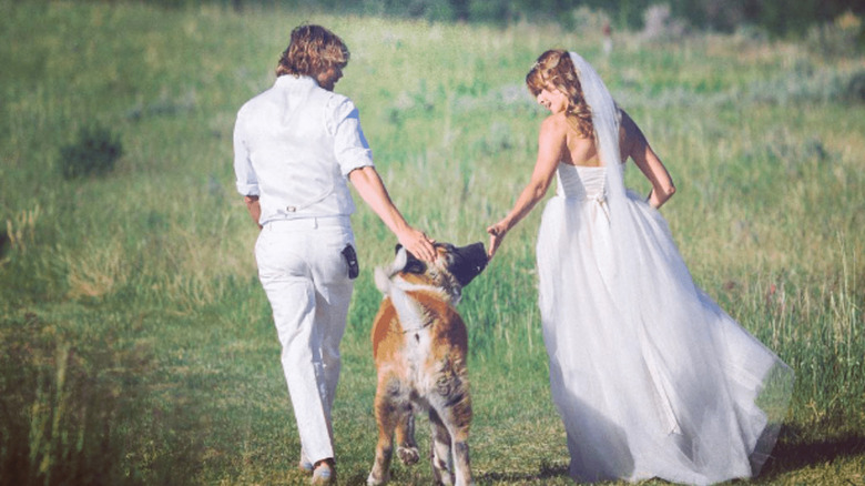 Eric Christian Olsen and Sarah Wright Olsen walking their dog through a field