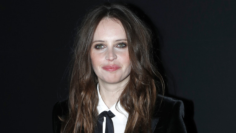 Felicity Jones in a black suit and smoky eye smiling (2019)