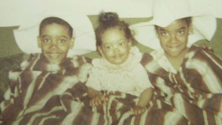 Toddler Gina Torres sitting between her siblings