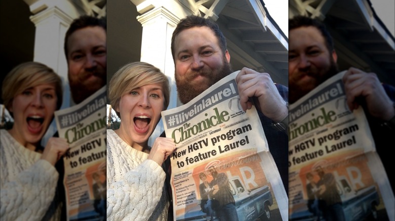 Erin and Ben Napier holding up a local newspaper featuring their new HGTV show