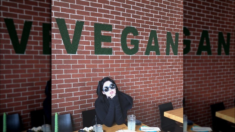 Kat Von D in front of a "vegan" sign