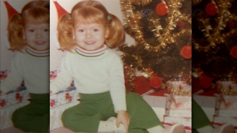 Kelly Ripa as toddler next to Christmas tree