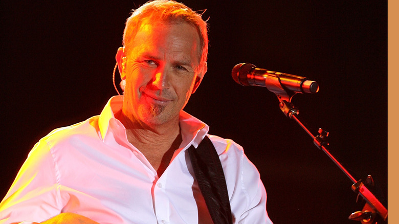 Kevin Costner playing guitar onstage