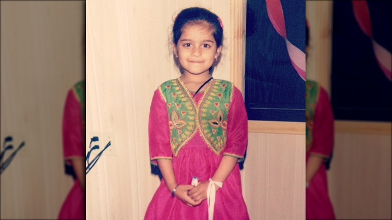 Lilly Singh as a young girl in a pink dress