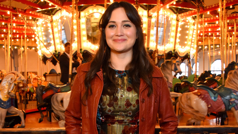 Lily Gladstone in front of a carousel