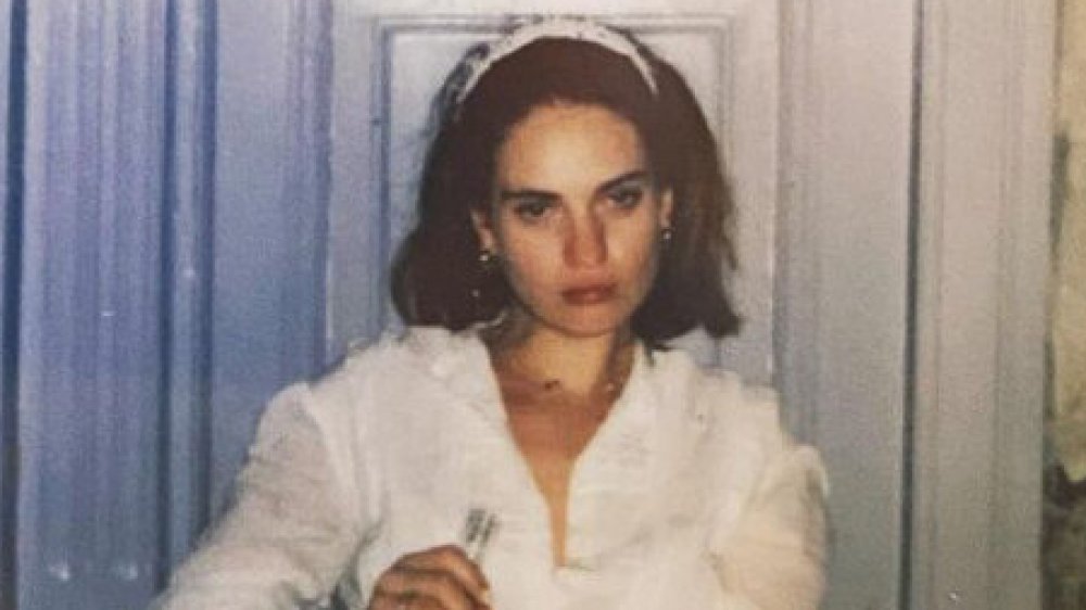 Lily James holding a bottle, looking sullen