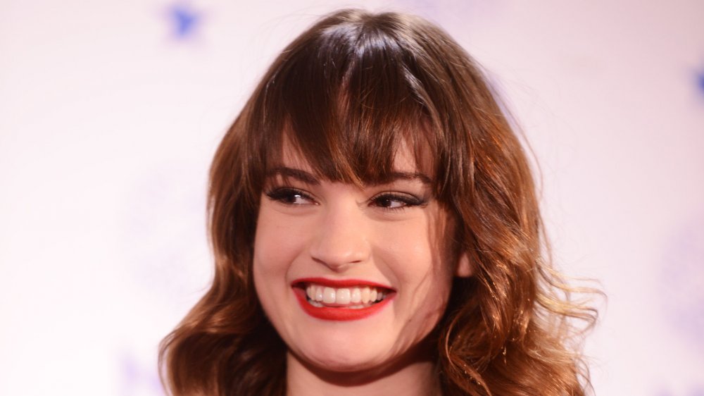 Lily James wearing red lipstick, smiling