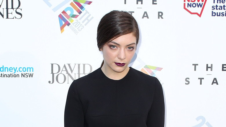 Lorde wearing black looking down