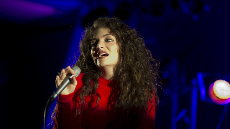 Lorde singing on stage wearing red