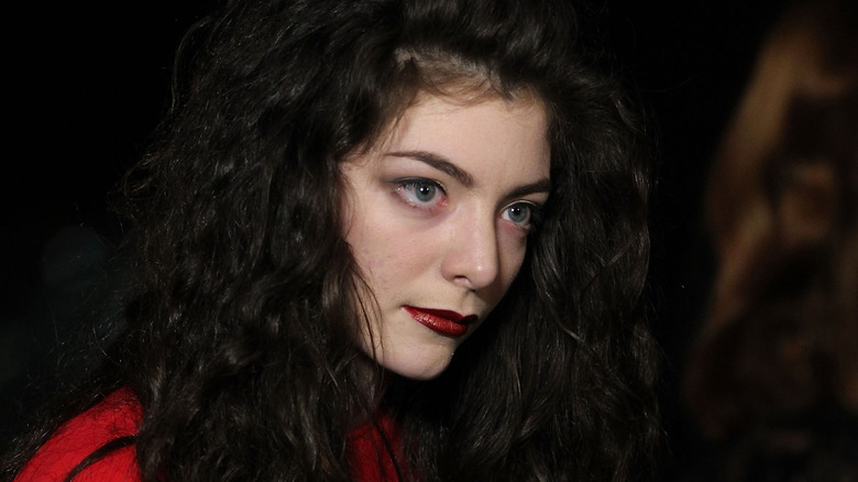 Lorde wearing red looking to the side