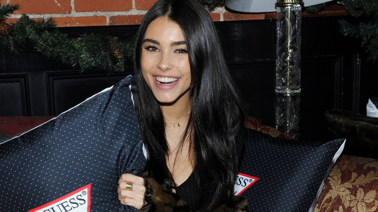 Madison Beer laughing and holding a GUESS pillow