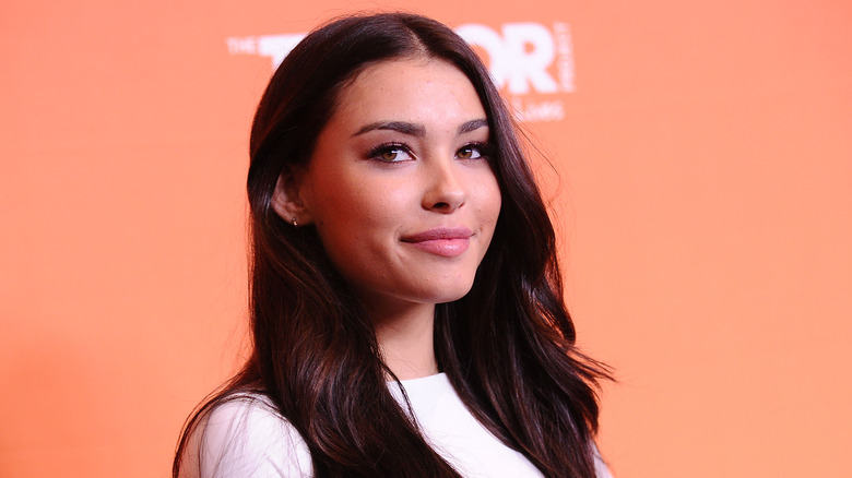 Madison Beer against an orange backdrop, posing