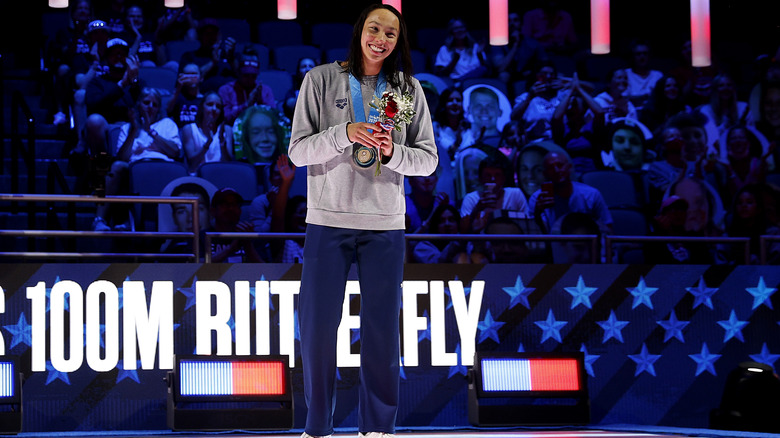 Torri Huske smiles on stage and holds flowers 