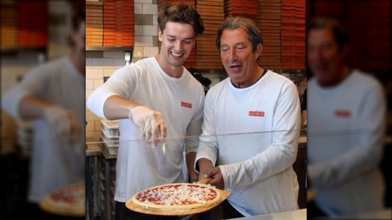 Patrick Schwarzenegger adding cheese to a pizza