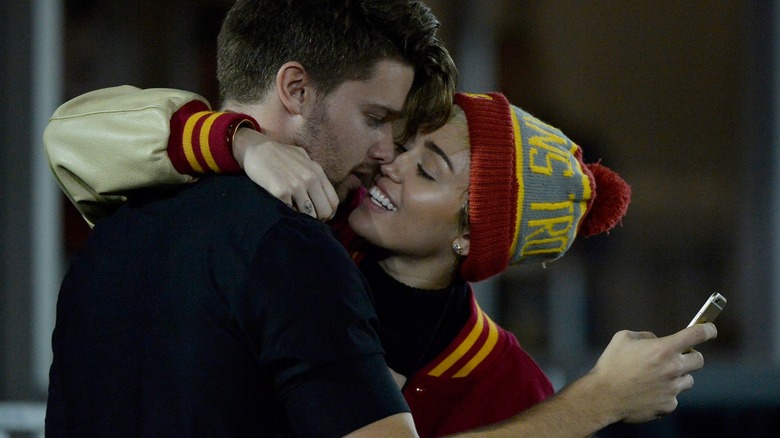 Patrick Schwarzenegger texting while Miley Cyrus tries to kiss him