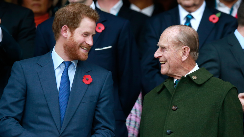 Prince Harry standing between his grandparents