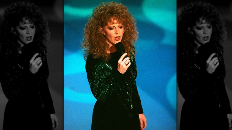 Reba McEntire singing on stage against blue background