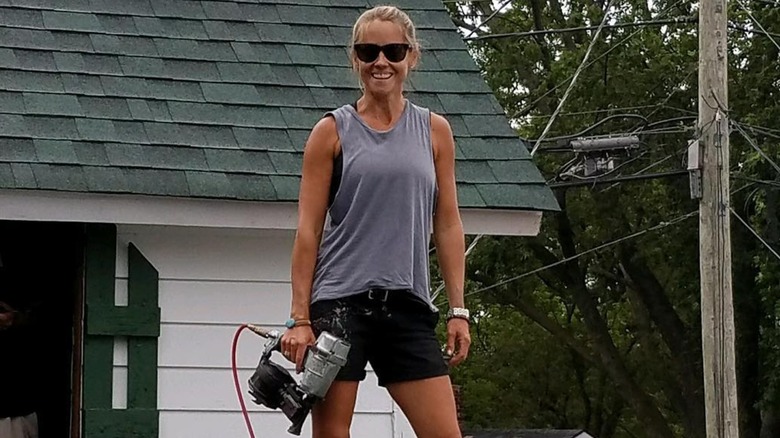 Nicole Curtis standing on a roof with a tool