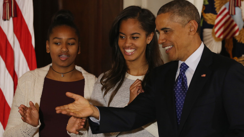 Sasha Obama smiling with her sister and dad