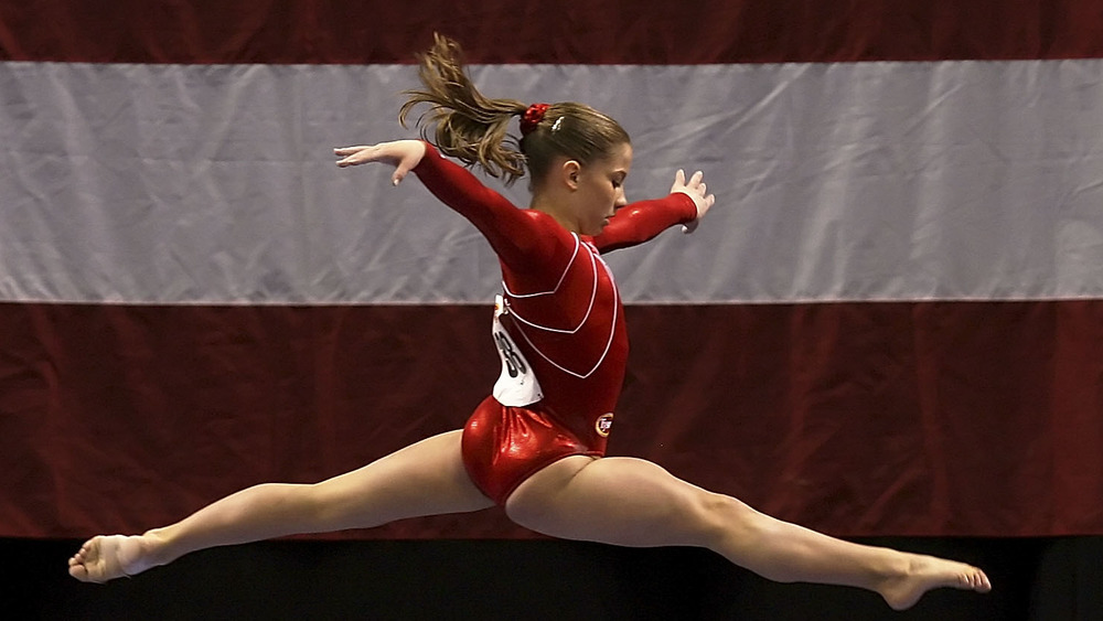 Shawn Johnson leaping over a beam