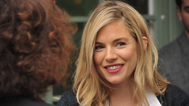 Sienna Miller looking askance and smiling