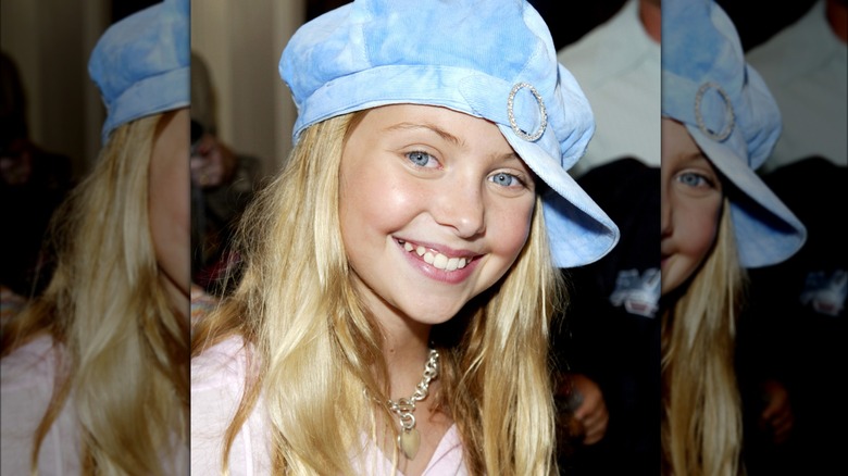 Young Taylor Momsen smiling in a blue hat 