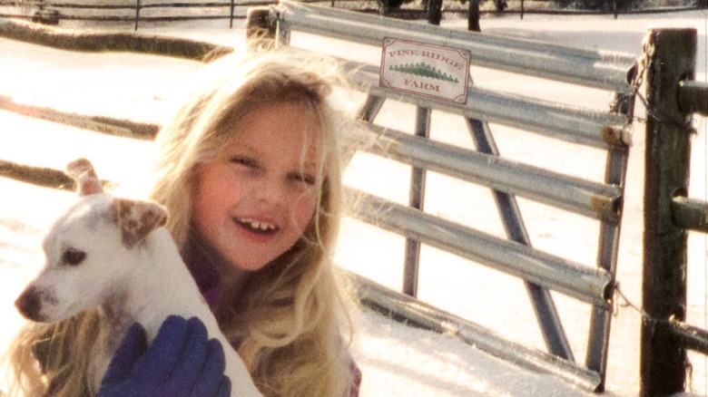 Child Taylor Swift holding a dog in the snow