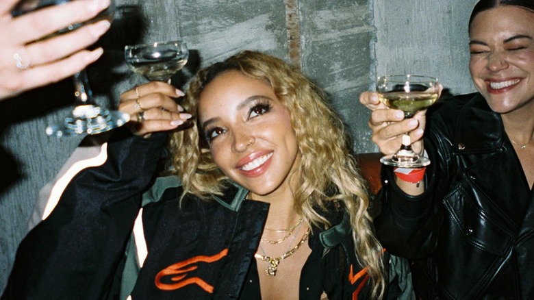 Tinashe raising a glass of champagne