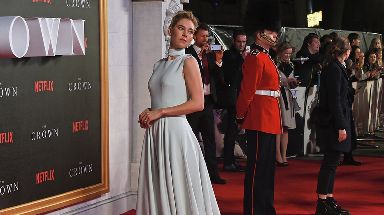 Vanessa Kirby posing on "The Crown" premier red carpet next to a Yeoman Warder