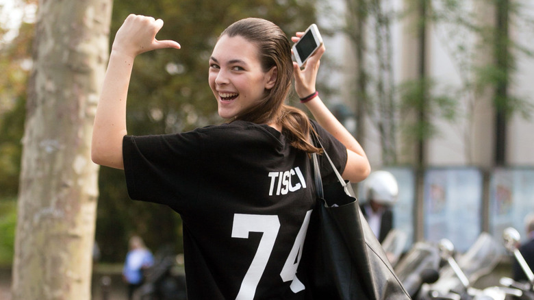 Vittoria Ceretti smiling while pointing to the back of her shirt