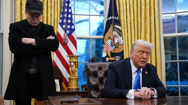 Elon Musk frowning in the Oval Office with president Donald Trump