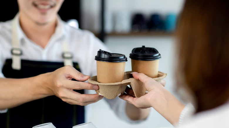 Barista hands person coffee at a coffee shop