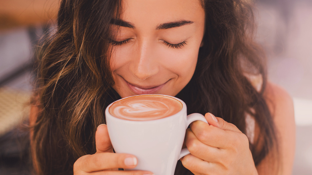 Woman smiling as she holds a cup of coffee