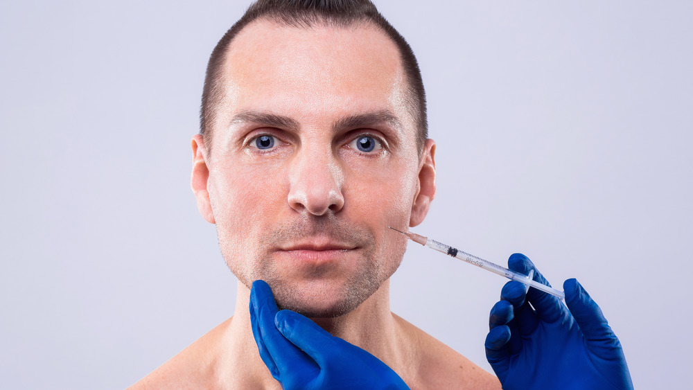 A male receiving a Botox injection in his cheek 