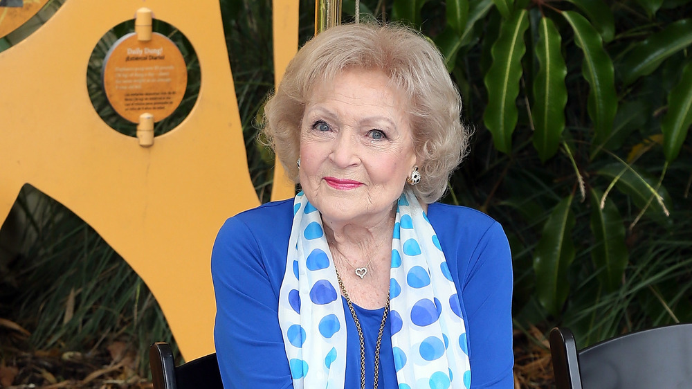 Betty White sitting outside wearing a blue top 