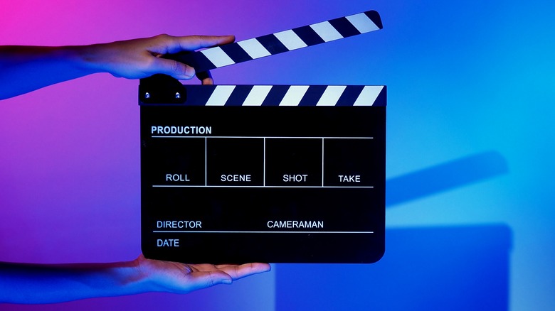 hands with film slate on blue and purple background