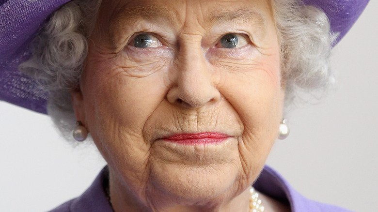 Queen Elizabeth II looking up wearing purple hat