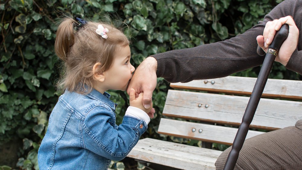 A little girl kissing an elderly persons hand