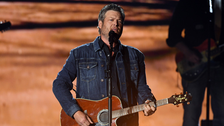 Blake performing a country song on stage with his guitar. 