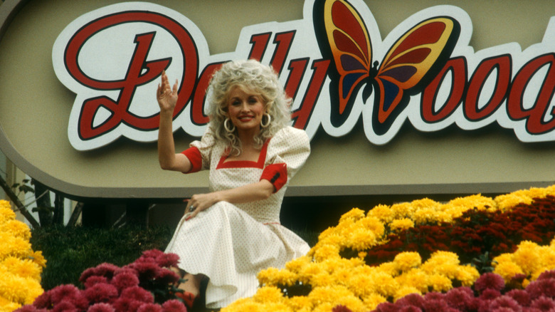 Dolly Parton posing Dollywood sign flowers