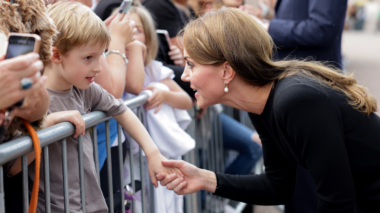 Catherine Middleton leans over to a speak to a young mourner