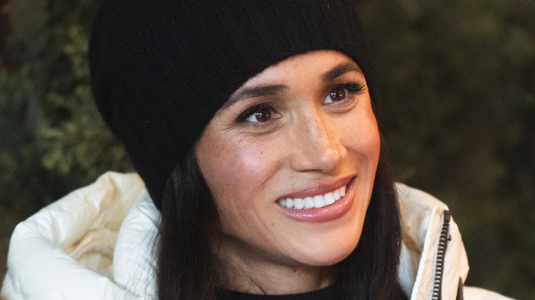 Meghan Markle smiling in a black beanie