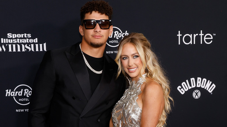 Brittany Mahomes and Patrick Mahomes pose for photos on a red carpet