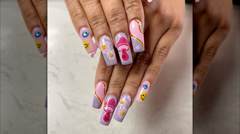 Hands showing nail set featuring smiley-faces, mushrooms, and flowers