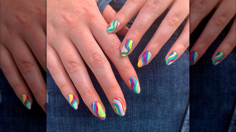 Hands with multicolored swirl nail designs