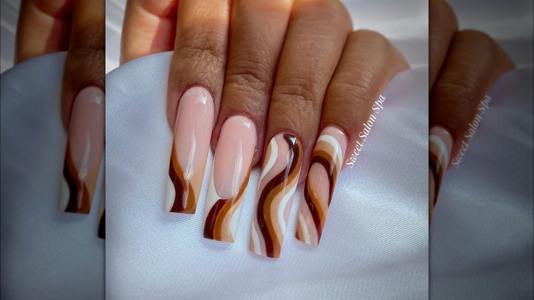 Hand showing brown, beige, and white nail design