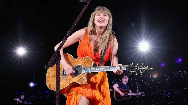 Taylor Swift smiling, playing guitar