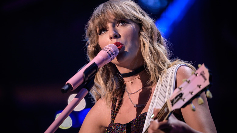 Taylor Swift playing guitar and performing