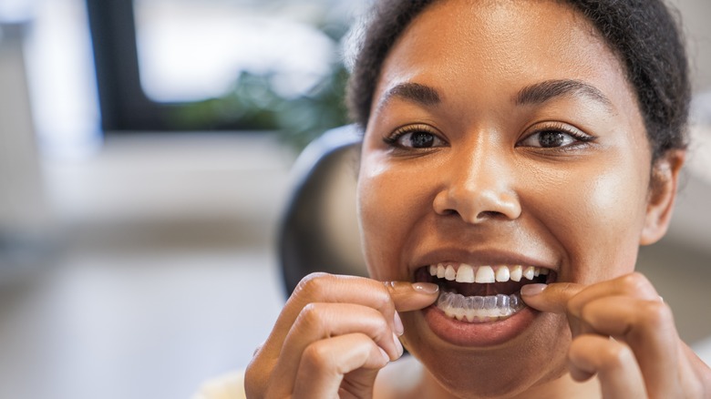 A woman applying teeth whitening strips 