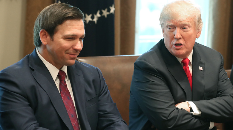 Ron DeSantis sits next to Donald Trump